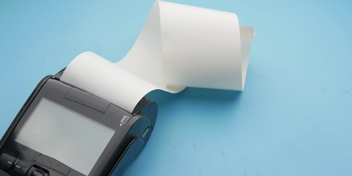Rouleau de papier thermique qui sort d'un terminal de paiement, sur fond bleu
