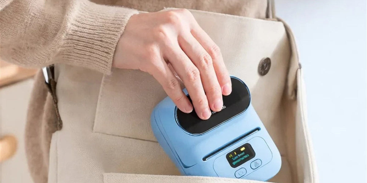 Imprimante thermique portable Phomemo M110 bleue glissée d'une main dans un sac en toile