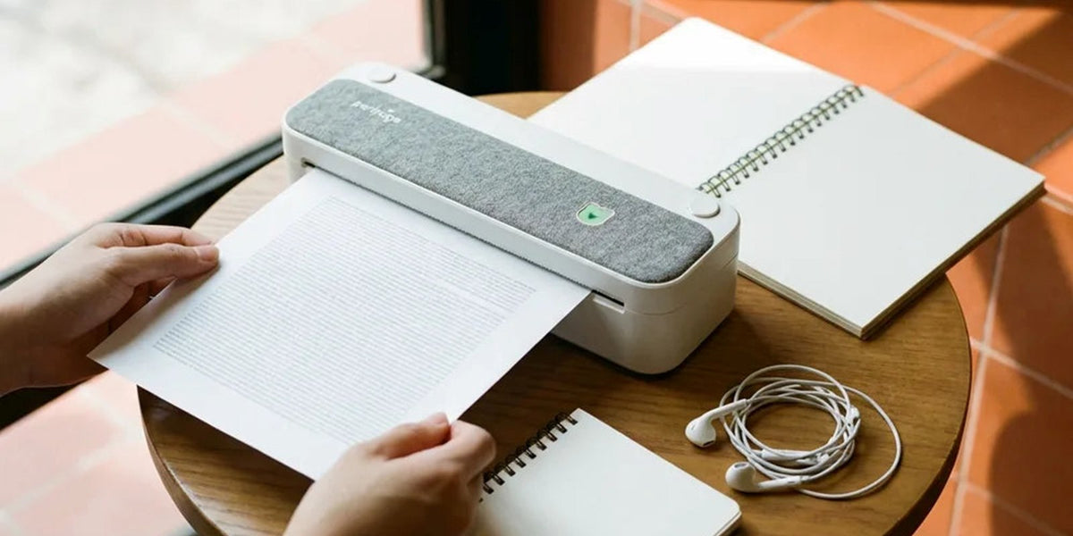 Mains qui récupèrent une page A4 imprimée par une imprimante thermique portable, sur une table de café