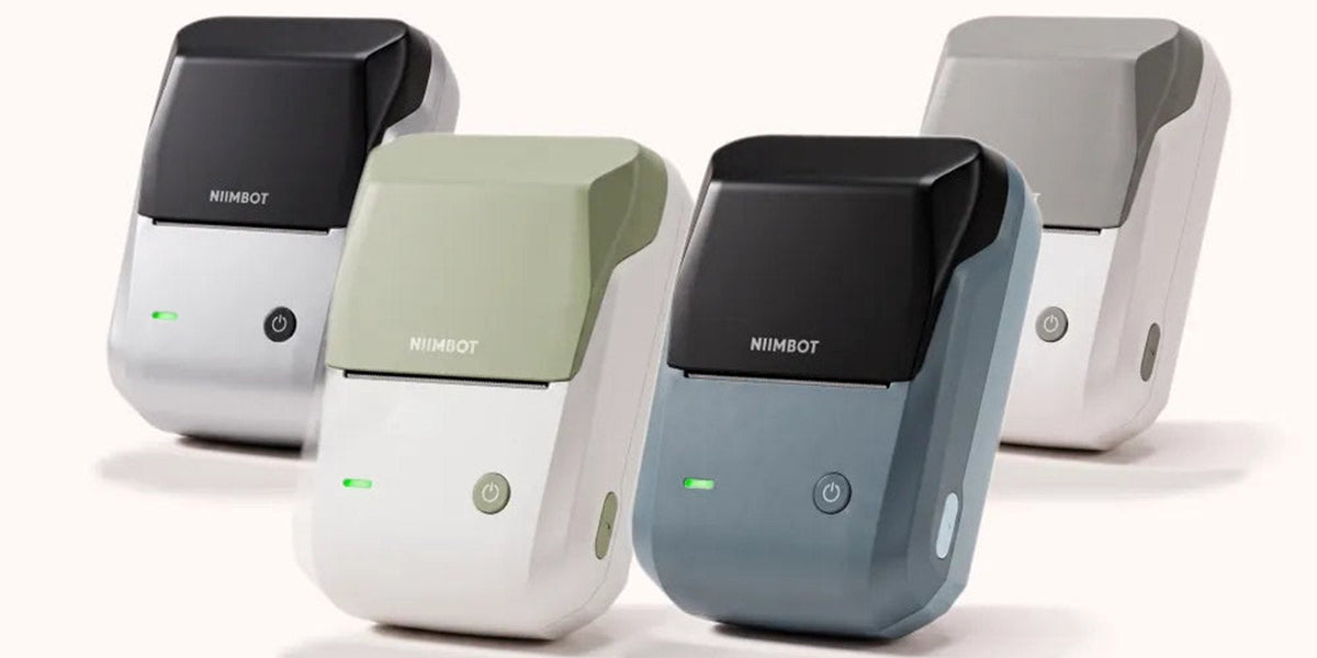 Quatre imprimantes thermiques portables NIIMBOT B1, verte, bleu foncé, grise et argent, réunies sur fond clair