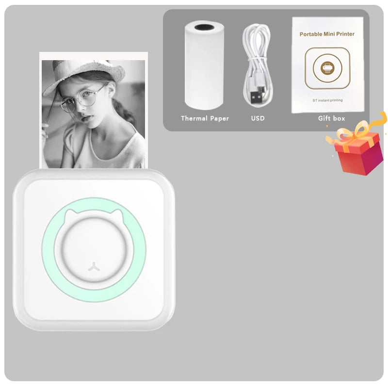 Contenu du coffret : mini imprimante blanche à anneau vert, rouleau thermique, câble USB et boîte cadeau