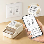Main tenant un smartphone affichant l'appli, imprimante crème sur un bureau et interrupteur mural étiqueté