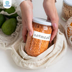Mains déposant un bocal de lentilles corail étiqueté oatmeal dans un sac en coton, près de filets de fruits