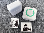 Mini imprimante blanche fermée et modèle à anneau vert, entourés de photos noir et blanc imprimées