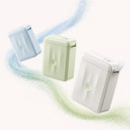 Imprimante thermique portable design NIIMBOT D110M en trois coloris flottants : bleu glacier, vert sauge et blanc cassé, étiquette qui sort du modèle blanc