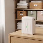 Imprimante NIIMBOT D110M blanche sur une commode, placard à linge aux paniers étiquetés de pictogrammes en arrière-plan