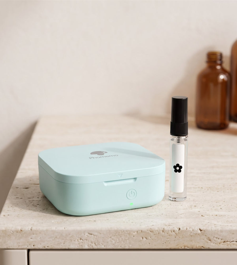 Imprimante Phomemo Q30 vert menthe sur un comptoir de parfumerie, échantillon de parfum étiqueté d'une fleur